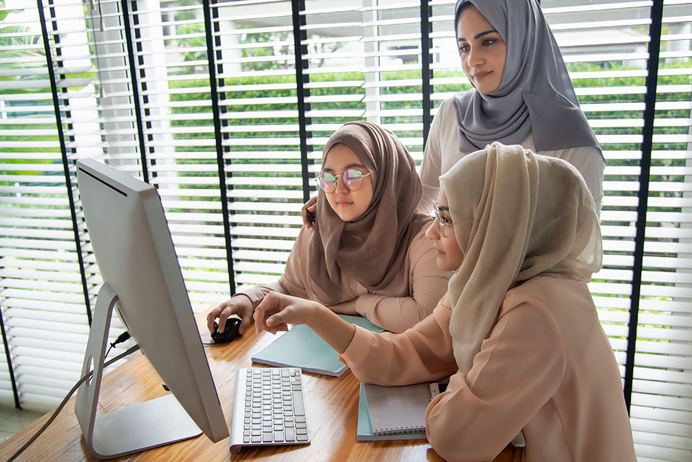 Tre kvinnor som arbetar framför en datorskärm
